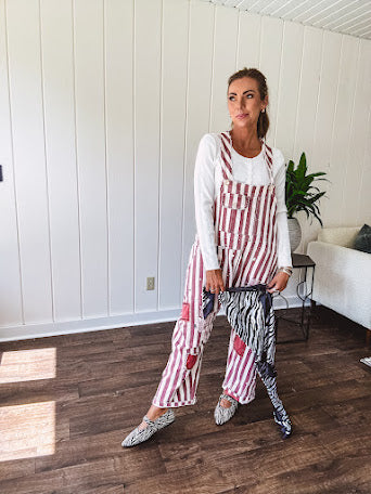Cream and crimson striped overalls with button adjustable straps and sides with paint splatter and patchwork detail throughout.