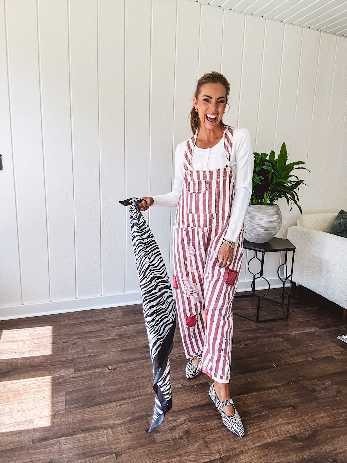 Cream and crimson striped overalls with button adjustable straps and sides with paint splatter and patchwork detail throughout.