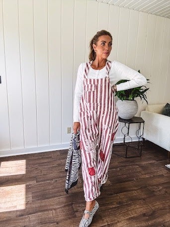 Cream and crimson striped overalls with button adjustable straps and sides with paint splatter and patchwork detail throughout.