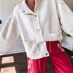 Soft cream snap front cardigan with front pockets and balloon style sleeves with ribbed collar.