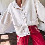 Soft cream snap front cardigan with front pockets and balloon style sleeves with ribbed collar.