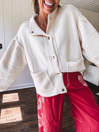 Soft cream snap front cardigan with front pockets and balloon style sleeves with ribbed collar.