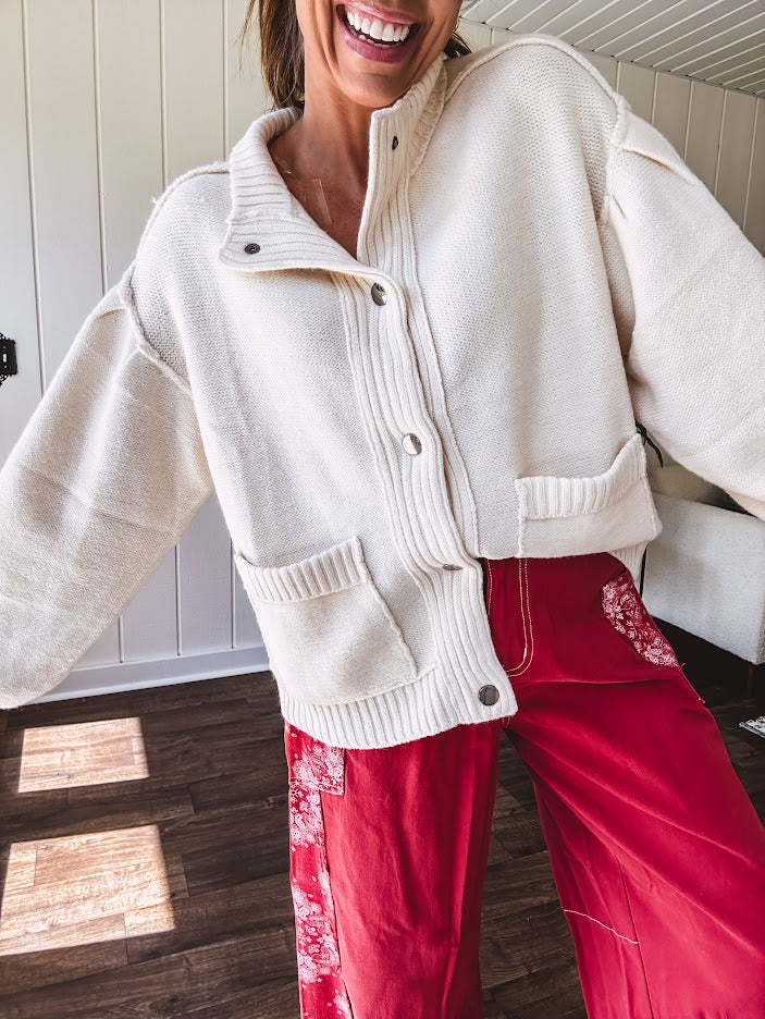 Soft, cozy cream snap button front cardigan with collar, exposed seam detail, balloon sleeves and front pockets.