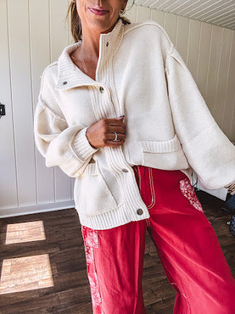 Soft cream snap front cardigan with front pockets and balloon style sleeves with ribbed collar.