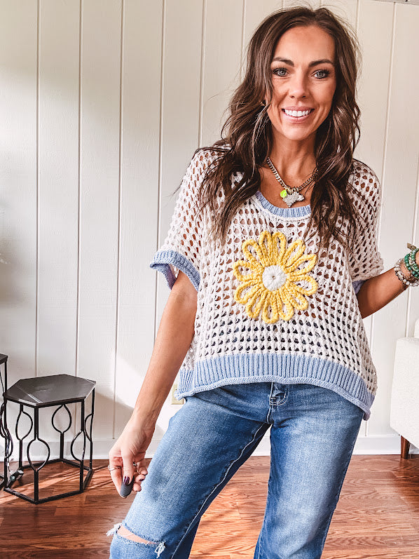 Open weave crochet sweater with 3/4 sleeves and large contrasting crochet flower on the front and contrasting trim. Oversized. Available in multiple colors.