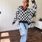 Lightweight black and white checkered long sleeve pullover with contrasting black V neck and cutout hem, with pockets.