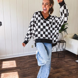 Lightweight black and white checkered long sleeve pullover with contrasting black V neck and cutout hem, with pockets.