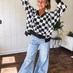 Lightweight black and white checkered long sleeve pullover with contrasting black V neck and cutout hem, with pockets.