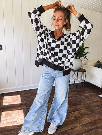 Lightweight black and white checkered long sleeve pullover with contrasting black V neck and cutout hem, with pockets.