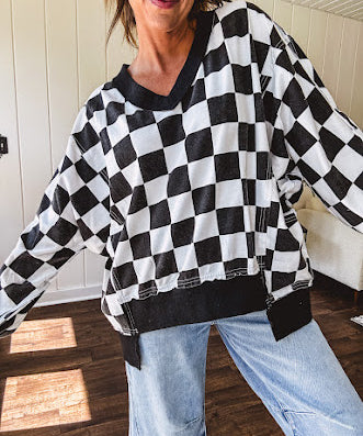 Lightweight black and white checkered long sleeve pullover with contrasting black V neck and cutout hem, with pockets.