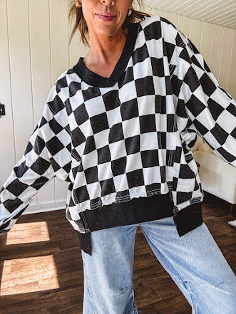 Lightweight black and white checkered long sleeve pullover with contrasting black V neck and cutout hem, with pockets.
