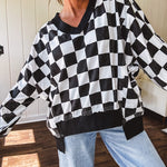 Lightweight black and white checkered long sleeve pullover with contrasting black V neck and cutout hem, with pockets.