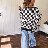 Lightweight black and white checkered long sleeve pullover with contrasting black V neck and cutout hem, with pockets.
