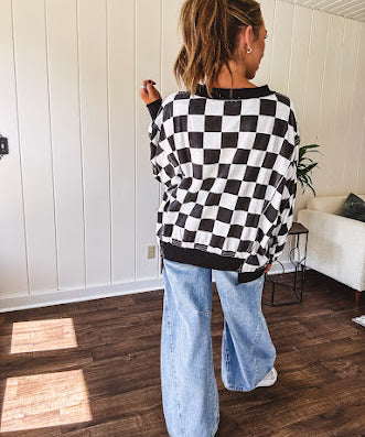 Lightweight black and white checkered long sleeve pullover with contrasting black V neck and cutout hem, with pockets.