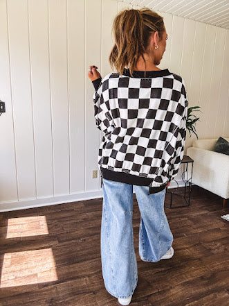 Lightweight black and white checkered long sleeve pullover with contrasting black V neck and cutout hem, with pockets.