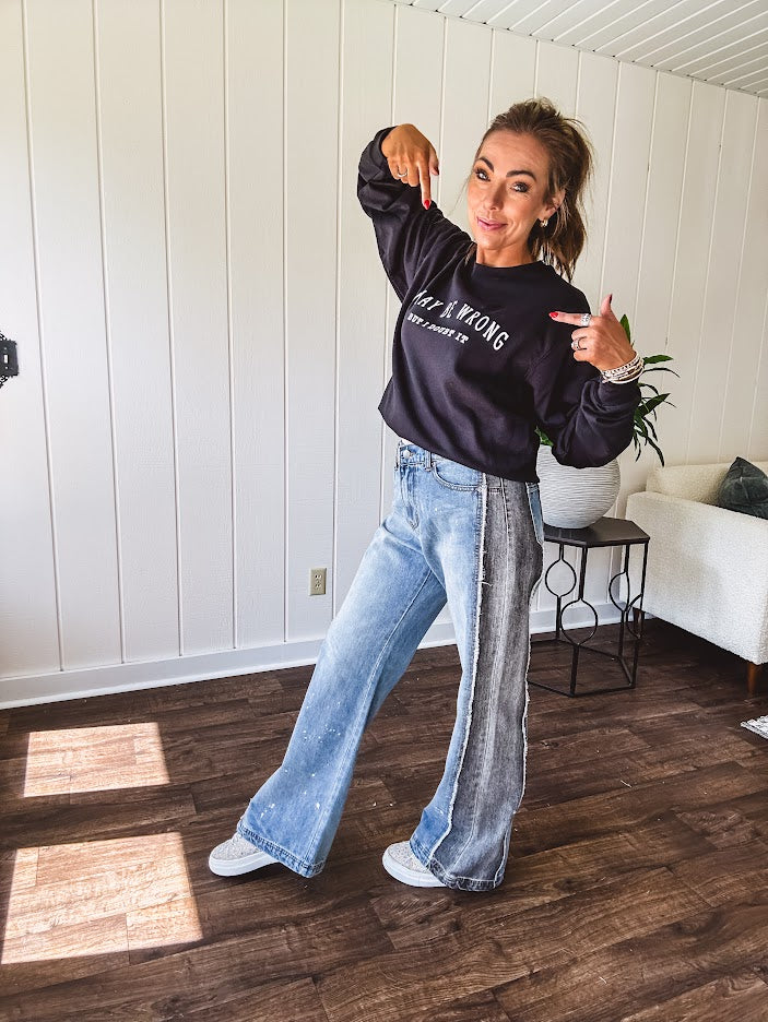 Wide leg medium washed denim pants featuring a washed black colorblock design on the outer legs and back pockets with exposed seams, bleach details and finished seams.