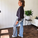 Wide leg medium washed denim pants featuring a washed black colorblock design on the outer legs and back pockets with exposed seams, bleach details and finished seams.