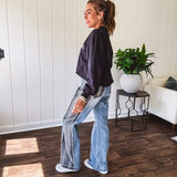 Wide leg medium washed denim pants featuring a washed black colorblock design on the outer legs and back pockets with exposed seams, bleach details and finished seams.
