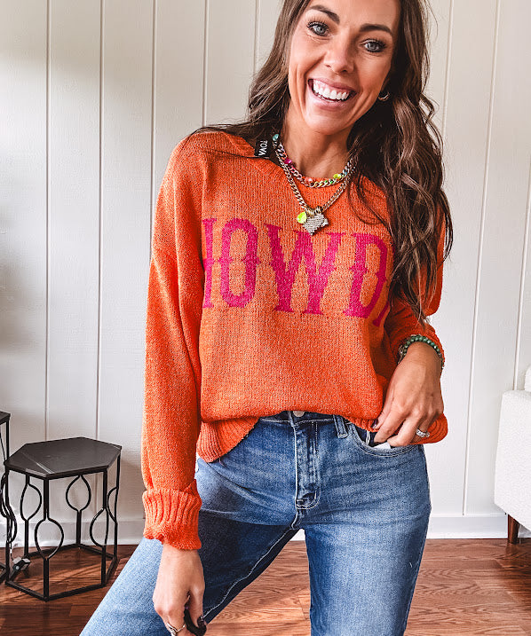 Lightweight, nearly sheer orange long sleeved sweater with hot pink "HOWDY" in western style graphic on front.