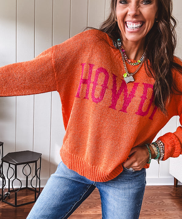 Lightweight, nearly sheer orange long sleeved sweater with hot pink "HOWDY" in western style graphic on front.