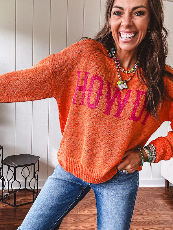 Lightweight, nearly sheer orange long sleeved sweater with hot pink "HOWDY" in western style graphic on front.