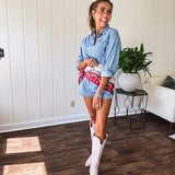 Lightweight light wash denim shorts romper with long sleeves, silver buttons down the front and classic collar with front pocket.