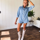 Lightweight light wash denim shorts romper with long sleeves, silver buttons down the front and classic collar with front pocket.