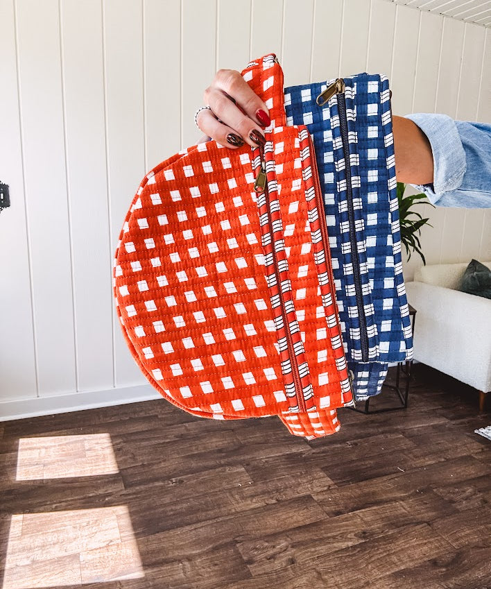 Quilted belt bag featuring zippered pockets and a gingham pattern available in several colors.
