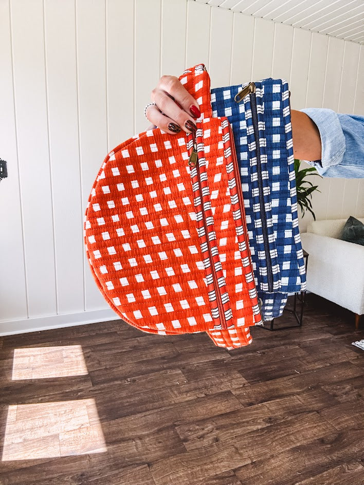 Quilted belt bag featuring zippered pockets and a gingham pattern available in several colors.