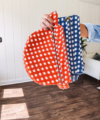 Quilted belt bag featuring zippered pockets and a gingham pattern available in several colors.