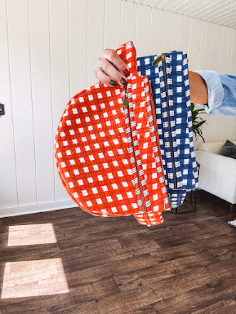 Quilted belt bag featuring zippered pockets and a gingham pattern available in several colors.