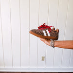 Mini leopard print sneakers with white stripes on the sides and contrasting red laces.