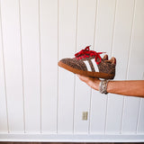 Mini leopard print sneakers with white stripes on the sides and contrasting red laces.