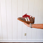 Mini leopard print sneakers with white stripes on the sides and contrasting red laces.