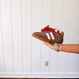 Mini leopard print sneakers with white stripes on the sides and contrasting red laces.
