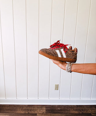 Mini leopard print sneakers with white stripes on the sides and contrasting red laces.