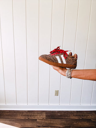 Mini leopard print sneakers with white stripes on the sides and contrasting red laces.
