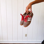 Mini leopard print sneakers with white stripes on the sides and contrasting red laces.