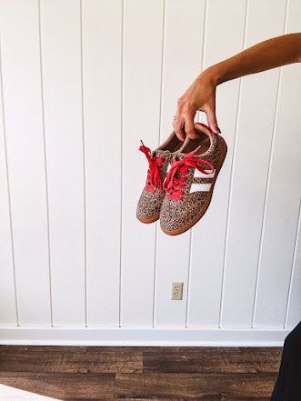 Mini leopard print sneakers with white stripes on the sides and contrasting red laces.
