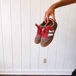 Mini leopard print sneakers with white stripes on the sides and contrasting red laces.