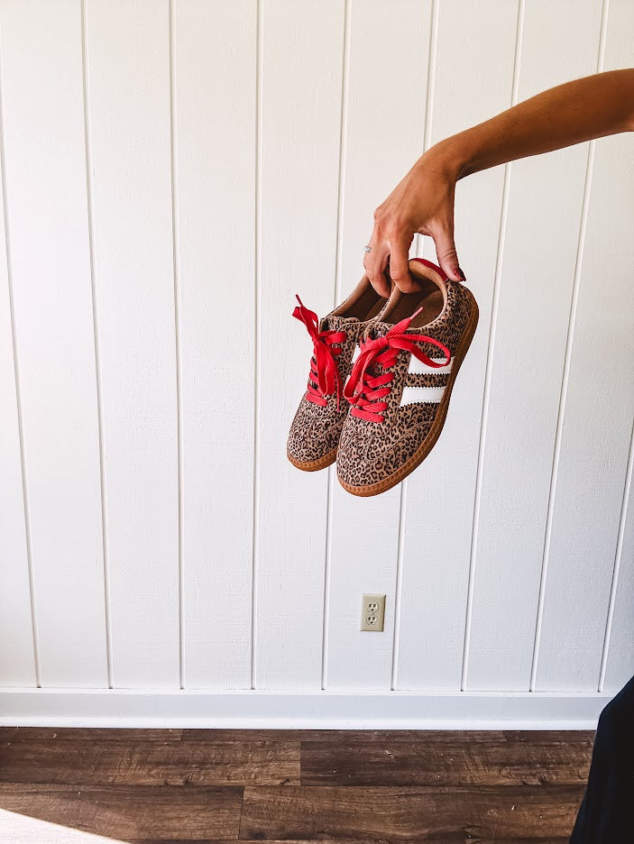 Mini leopard print sneakers with white stripes on the sides and contrasting red laces.