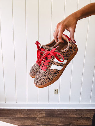Mini leopard print sneakers with white stripes on the sides and contrasting red laces.