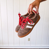 Mini leopard print sneakers with white stripes on the sides and contrasting red laces.