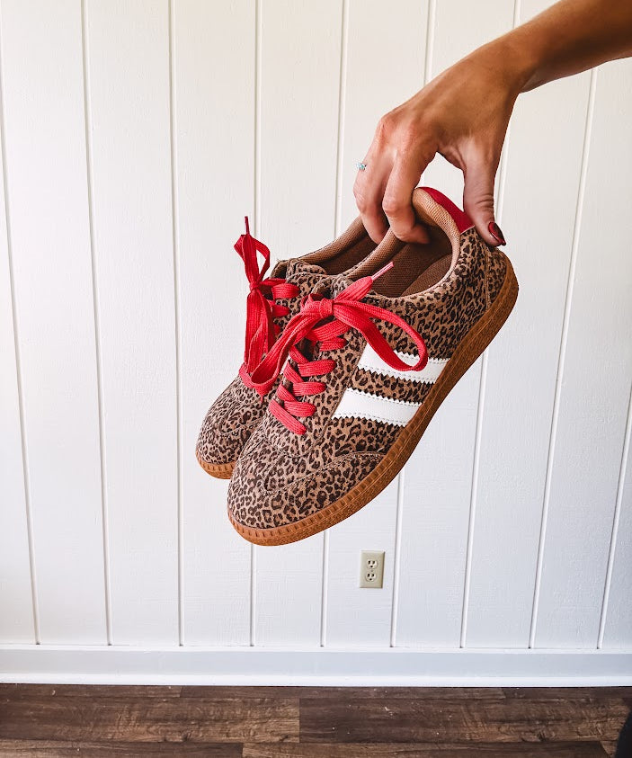 Mini leopard print sneakers with white stripes on the sides and contrasting red laces.