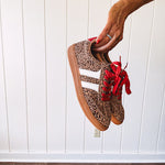 Mini leopard print sneakers with white stripes on the sides and contrasting red laces.