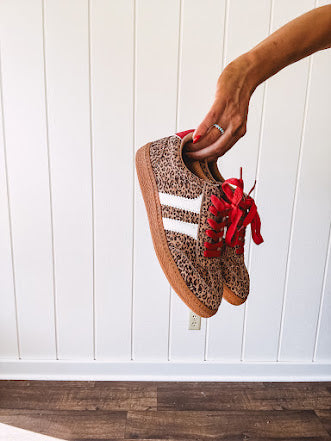Mini leopard print sneakers with white stripes on the sides and contrasting red laces.