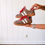 Mini leopard print sneakers with white stripes on the sides and contrasting red laces.