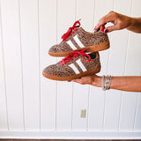 Mini leopard print sneakers with white stripes on the sides and contrasting red laces.