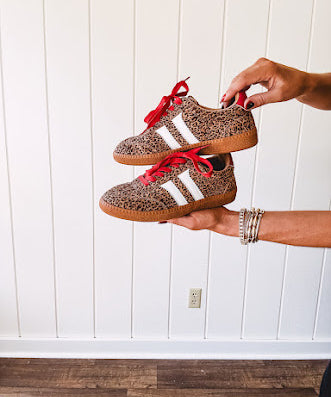 Mini leopard print sneakers with white stripes on the sides and contrasting red laces.
