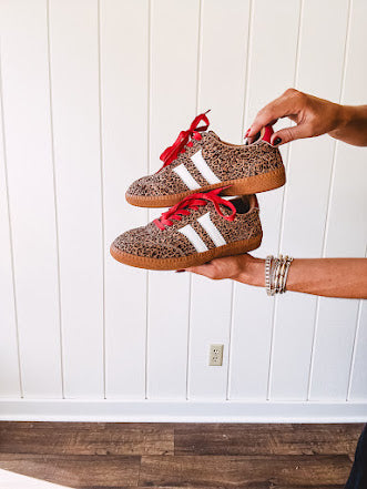 Mini leopard print sneakers with white stripes on the sides and contrasting red laces.
